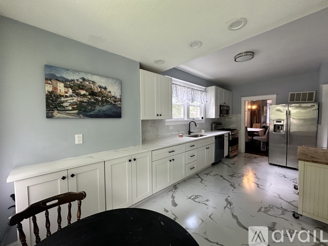 A kitchen with white cabinets and a marble floor.