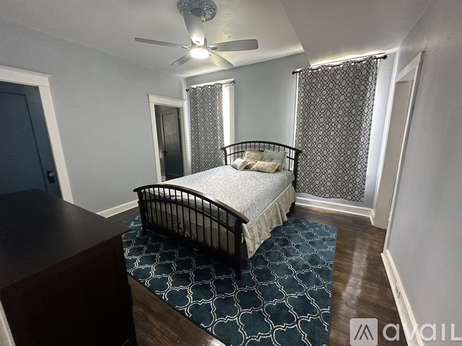A bedroom with a bed, a ceiling fan, and a patterned rug.