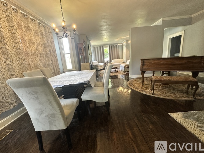A dining room with a table set for four and a chandelier hanging from the ceiling.