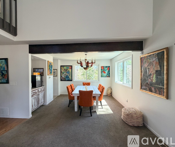 A dining room with a white table and orange chairs.