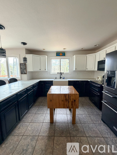 A kitchen with black cabinets and a wooden island.