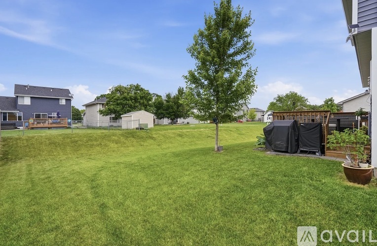 A grassy yard with a tree and a house in the background.