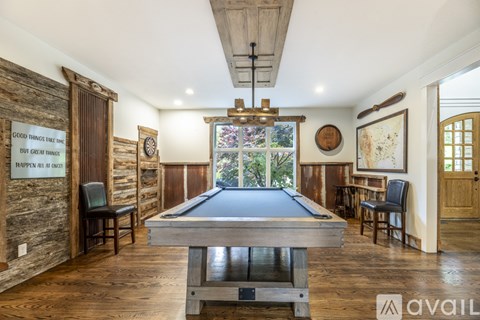 A pool table in the middle of a room with wooden floors and walls.