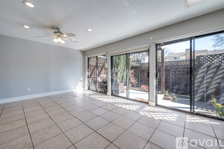 A spacious room with a ceiling fan and sliding glass doors.