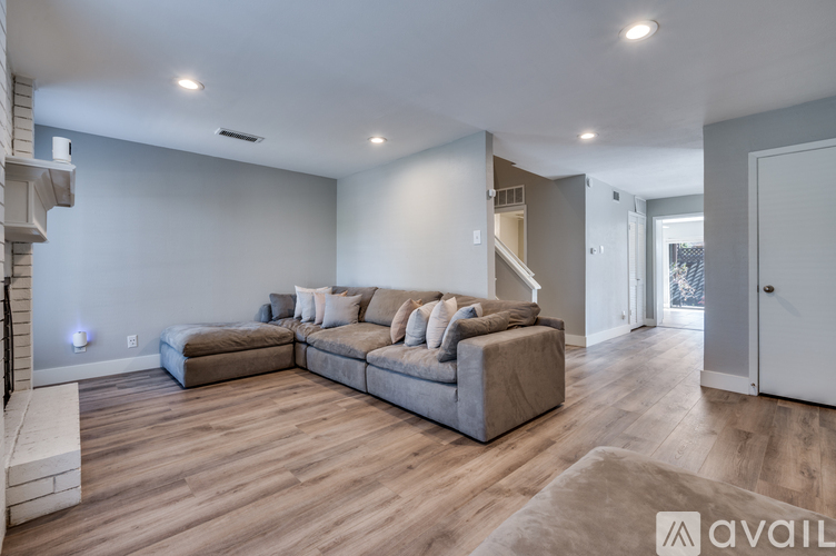 A spacious living room with a grey sofa and wooden flooring.