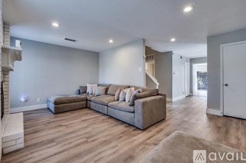 A spacious living room with a grey sofa and wooden flooring.
