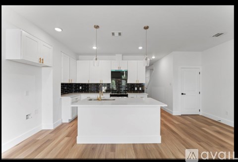 A modern kitchen with white cabinets and a wooden floor.