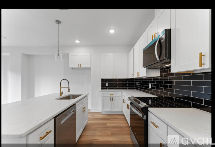 A modern kitchen with white cabinets and a black tile backsplash.