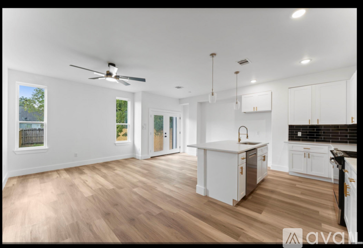 A kitchen with white cabinets and a wooden floor.