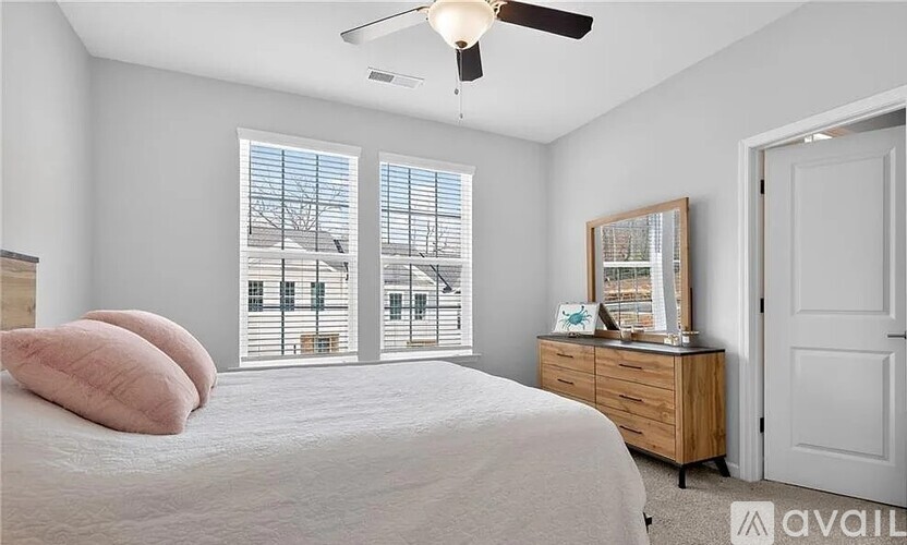 A bedroom with a bed, dresser, and window with blinds.