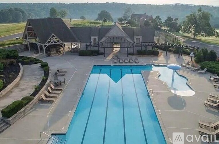 A large outdoor swimming pool with a slide and a building in the background.