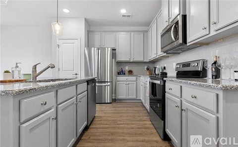 A kitchen with white cabinets and a wooden floor.