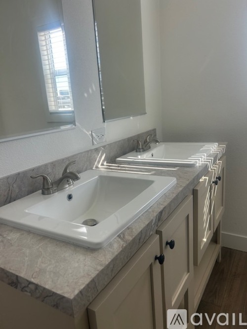 A bathroom with a marble countertop and a large mirror above a double sink.