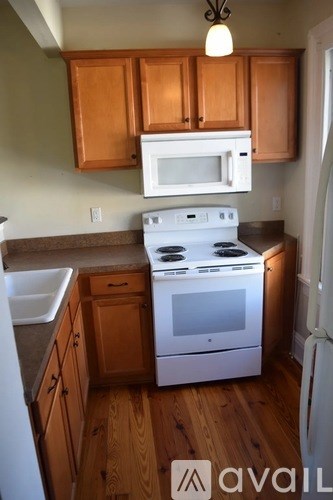 A kitchen with wooden cabinets and a white stove top oven.