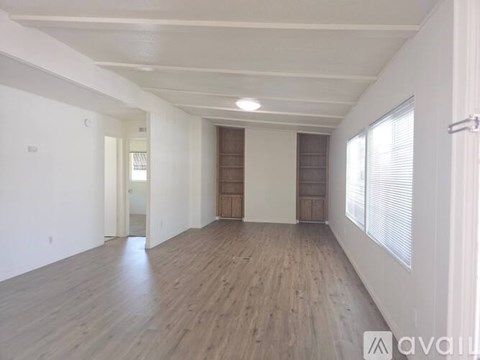 A spacious room with wooden floors and white walls.