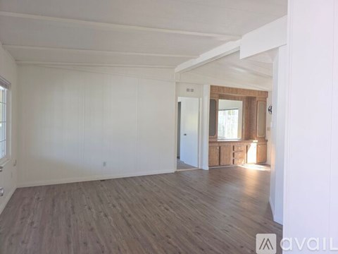 A spacious room with wooden flooring and white walls.