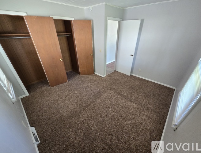 A room with brown carpet and a white wall with a door and a wardrobe.