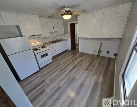 A kitchen with white cabinets and a wooden floor.