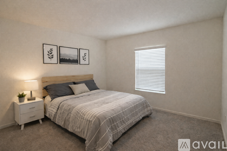 A bedroom with a bed, nightstand, and pictures on the wall.