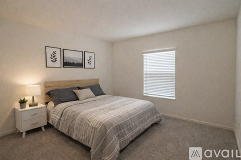 A bedroom with a bed, nightstand, and pictures on the wall.