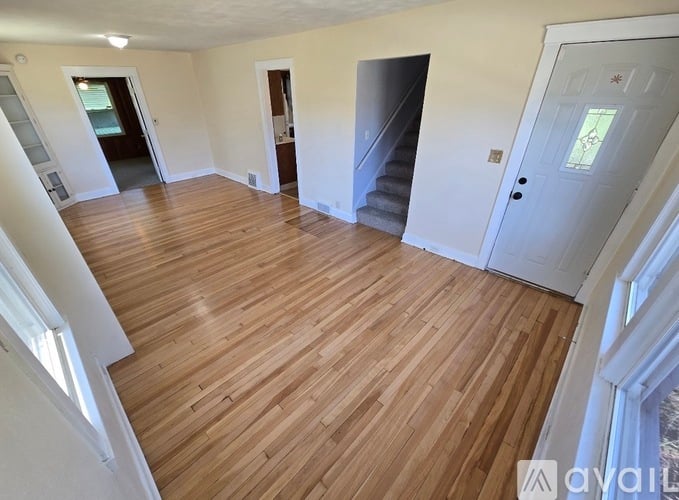 A spacious room with wooden flooring and white walls.