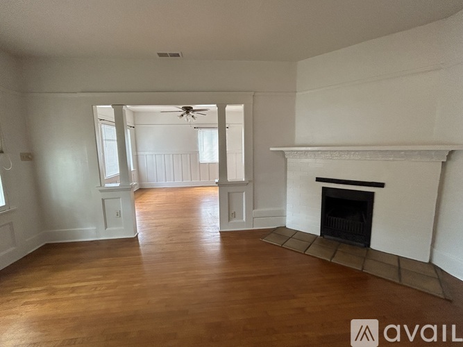 A spacious living room with a fireplace and a ceiling fan.