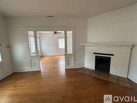 A spacious living room with a fireplace and a ceiling fan.