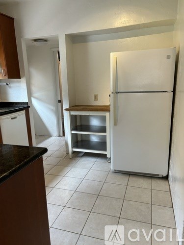 A kitchen with a white refrigerator and a black counter top.