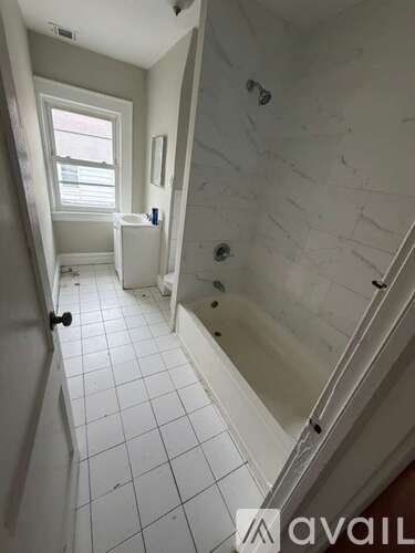 A bathroom with a white tiled floor and walls.