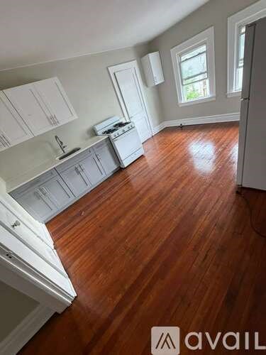 A kitchen with wooden floors and white cabinets.