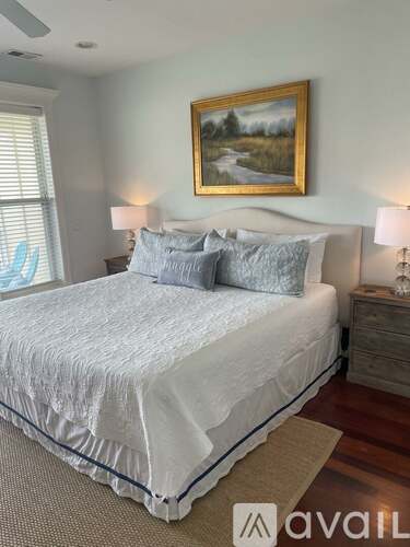 A bedroom with a large bed and a painting on the wall.