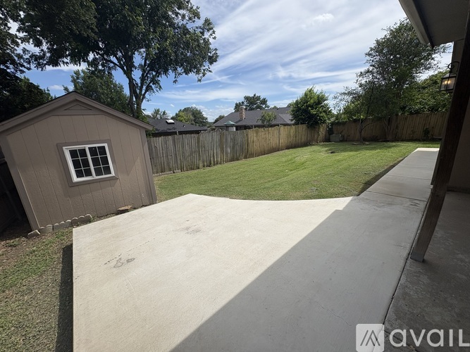 A backyard with a concrete walkway and a wooden fence.