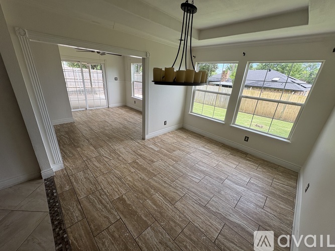 A room with a light brown floor and a chandelier hanging from the ceiling.
