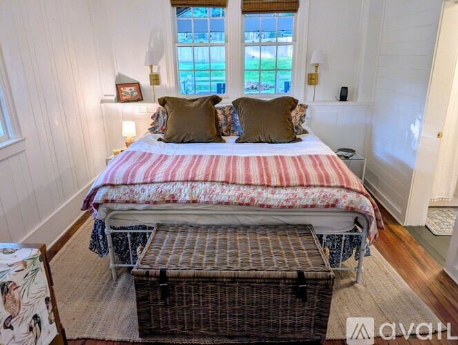 A bedroom with a large bed and a window overlooking a green area.