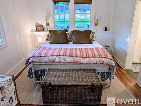A bedroom with a large bed and a window overlooking a green area.