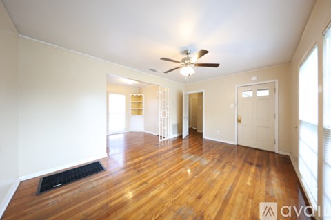 A spacious room with wooden floors and a ceiling fan.
