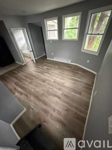 A room with wooden flooring and a window overlooking trees.