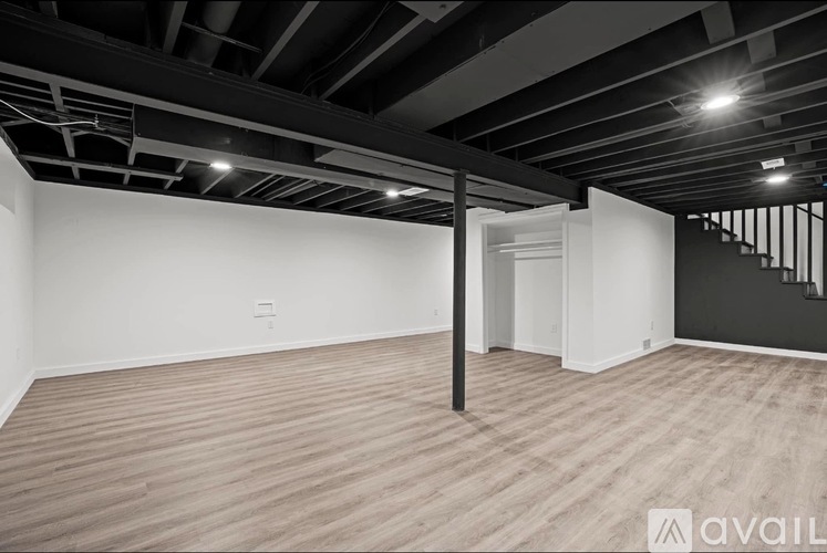 A spacious room with wooden flooring and a black and white color scheme.