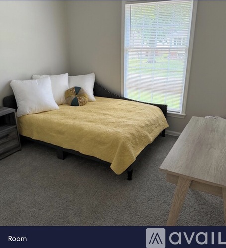A bedroom with a bed, nightstand, and window.