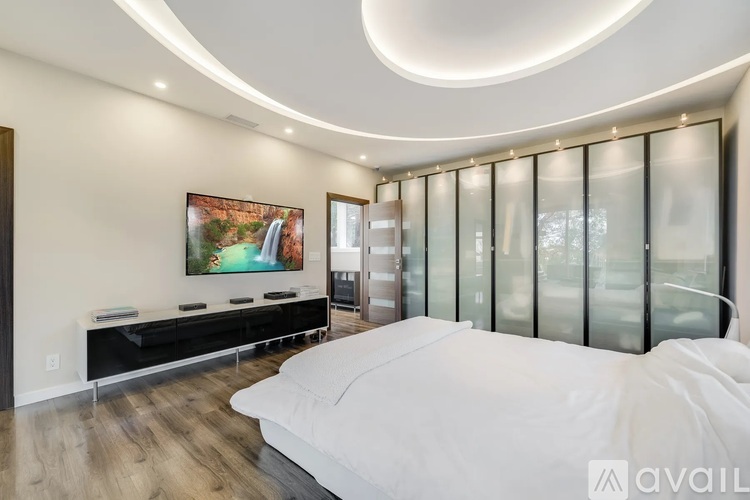 A modern bedroom with a large bed and a painting on the wall.