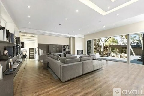 A spacious living room with a grey sofa and wooden flooring.
