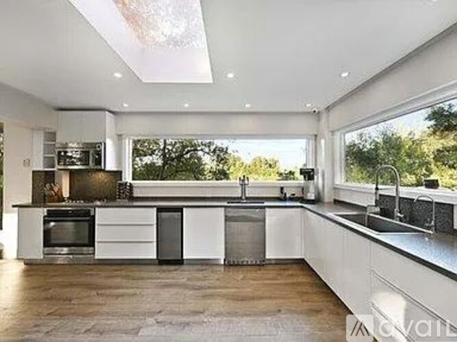 A modern kitchen with white cabinets and stainless steel appliances.