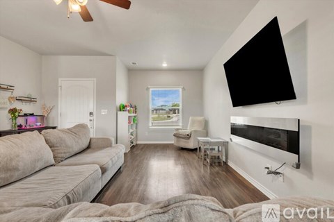 A living room with a large couch and a flat screen TV mounted on the wall.