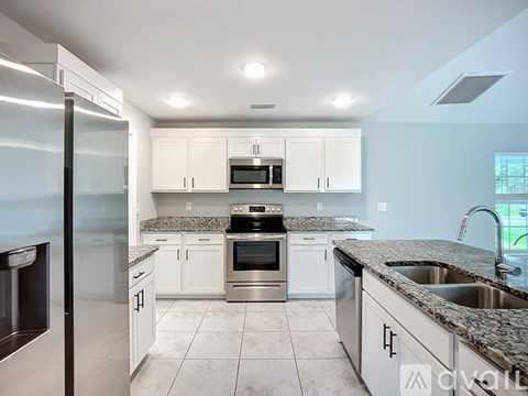 A modern kitchen with white cabinets and stainless steel appliances.