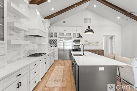A modern kitchen with a stainless steel refrigerator and wooden flooring.