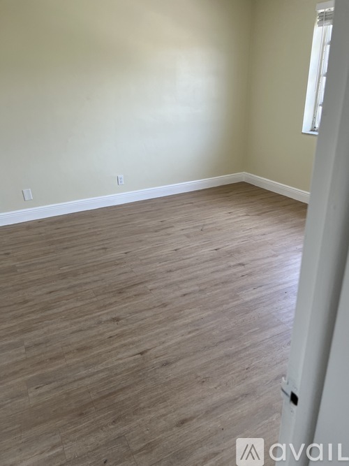 A room with wooden flooring and a white door.
