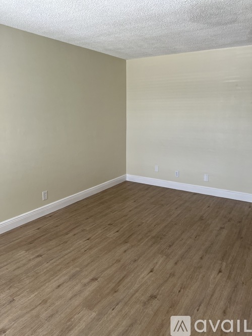 A room with wooden flooring and beige walls.