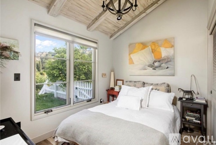 A bedroom with a large bed and a painting on the wall.