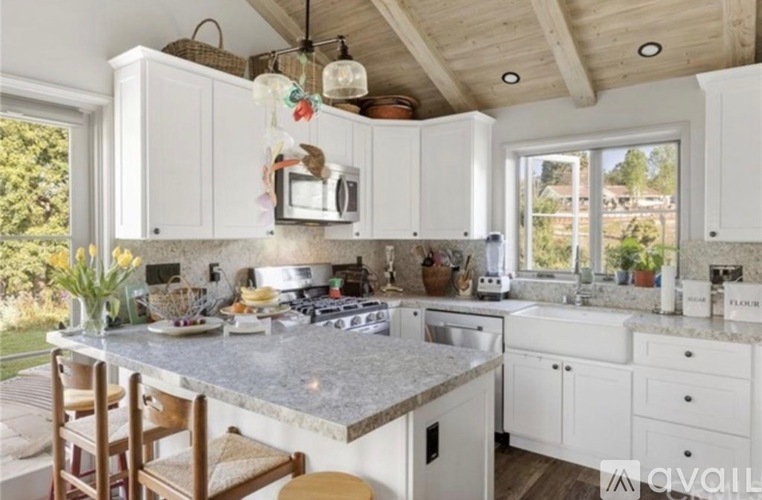 A kitchen with white cabinets and a granite countertop.