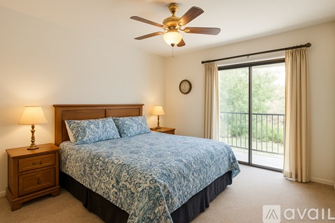 A bedroom with a bed, a ceiling fan, and a sliding glass door.